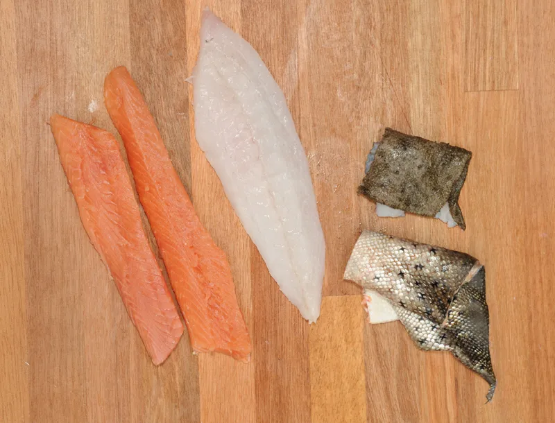 Cut in strips - When done the skin is off and the filet can be cut into two strips. Remove the lateral bones in the meat with tweezers or by trimming off a narrow band of meat with the bones in it. The white meat here is from a turbot, which is a very good alternative or supplement to the trout.